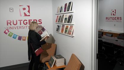 female reading a book near the door of the Rutgers University Press Office