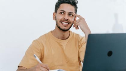 male student smiling by his laptop